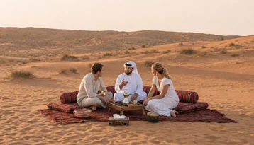 Emirati guide sharing traditional Arabic coffee and stories with visitors in the Abu Dhabi desert