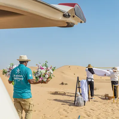 Mujeeb Rahman carrying floral arrangements while his team builds a private desert wedding setup in the Abu Dhabi dunes for Arabiers Holidays