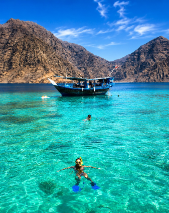 Traditional dhow sailing across turquoise Musandam fjord waters, featured in Seyed Shifaam's Musandam tour packages content for Arabiers