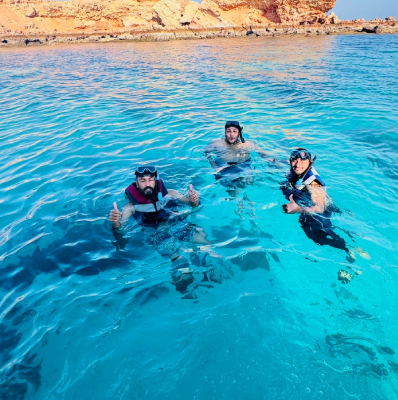 Seyed Shifaam snorkelling with two companions in clear turquoise water off the Daymaniyat Islands, Oman