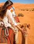 Traveller enjoying a camel ride across the Abu Dhabi desert dunes