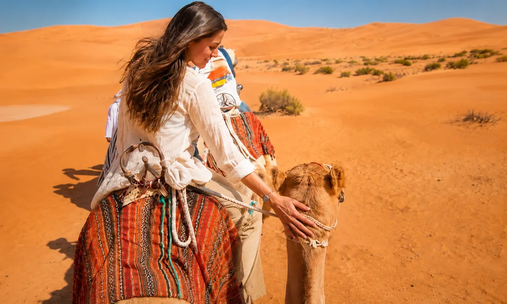 Traveller enjoying a camel ride across the Abu Dhabi desert dunes