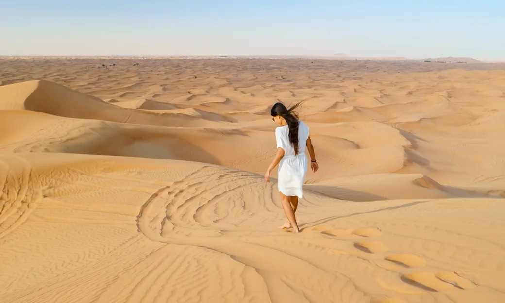 Traveller walking across Abu Dhabi desert dunes