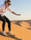 Traveller sandboarding down an Al Khatim dune during an Abu Dhabi morning safari