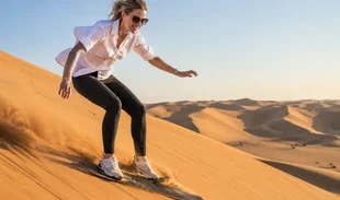 Traveller sandboarding down an Al Khatim dune during an Abu Dhabi morning safari