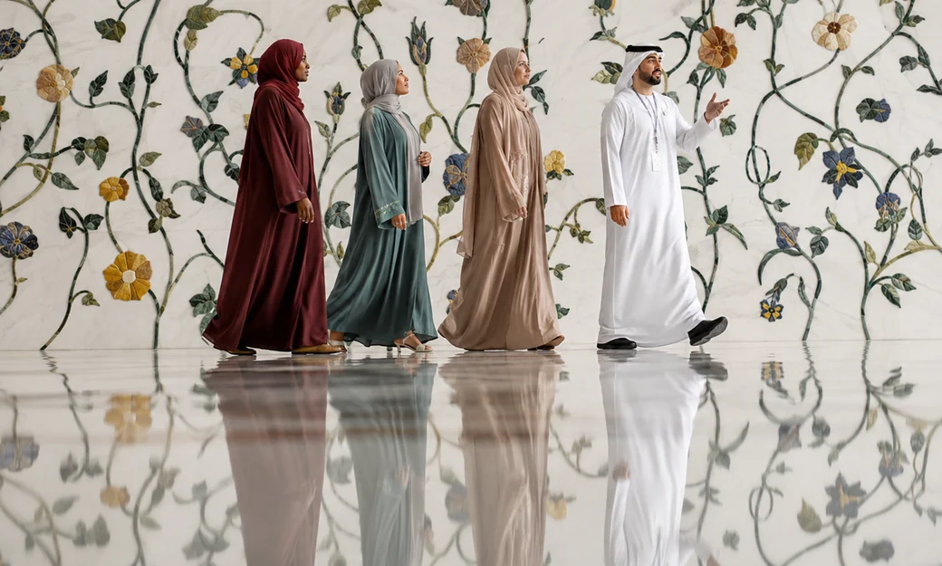 Guide leading visitors beside the floral marble wall at Sheikh Zayed Grand Mosque