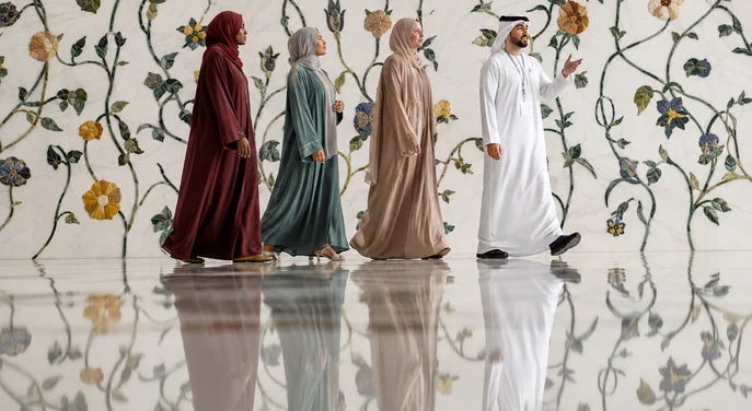Guide leading visitors beside the floral marble wall at Sheikh Zayed Grand Mosque