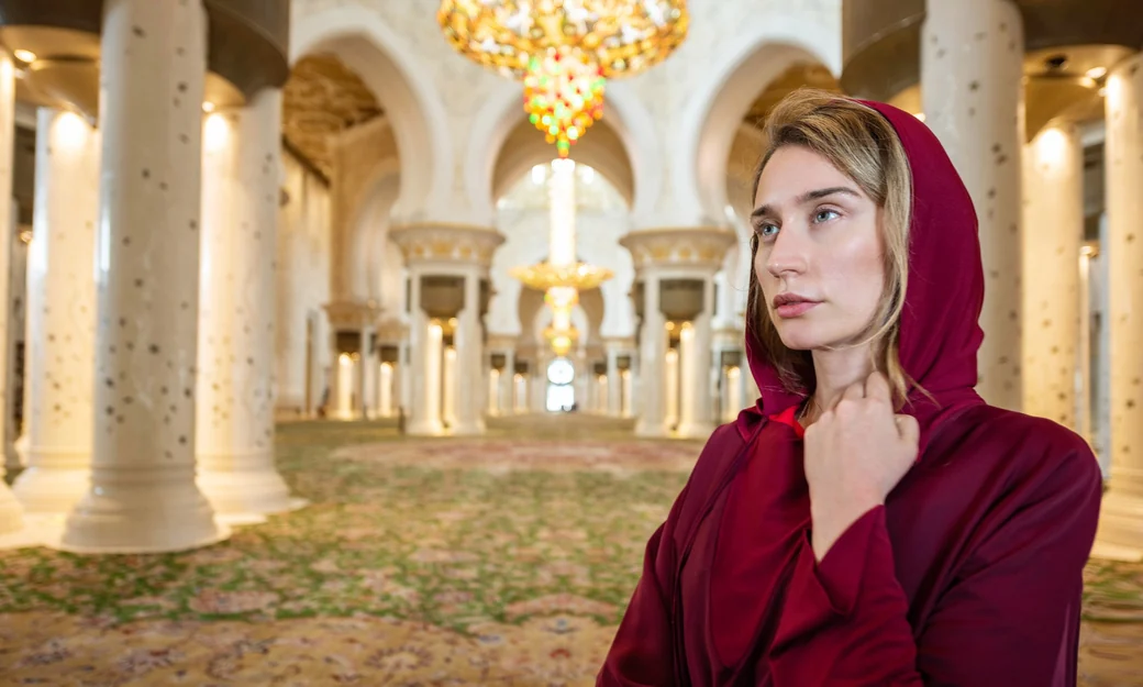Visitor wearing a red headscarf inside Sheikh Zayed Grand Mosque in Abu Dhabi