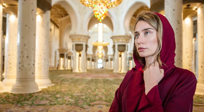 Visitor wearing a red headscarf inside Sheikh Zayed Grand Mosque in Abu Dhabi