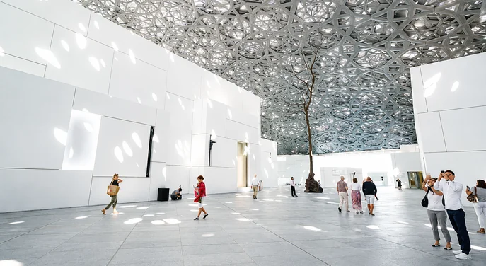 Visitors beneath the geometric dome inside Louvre Abu Dhabi