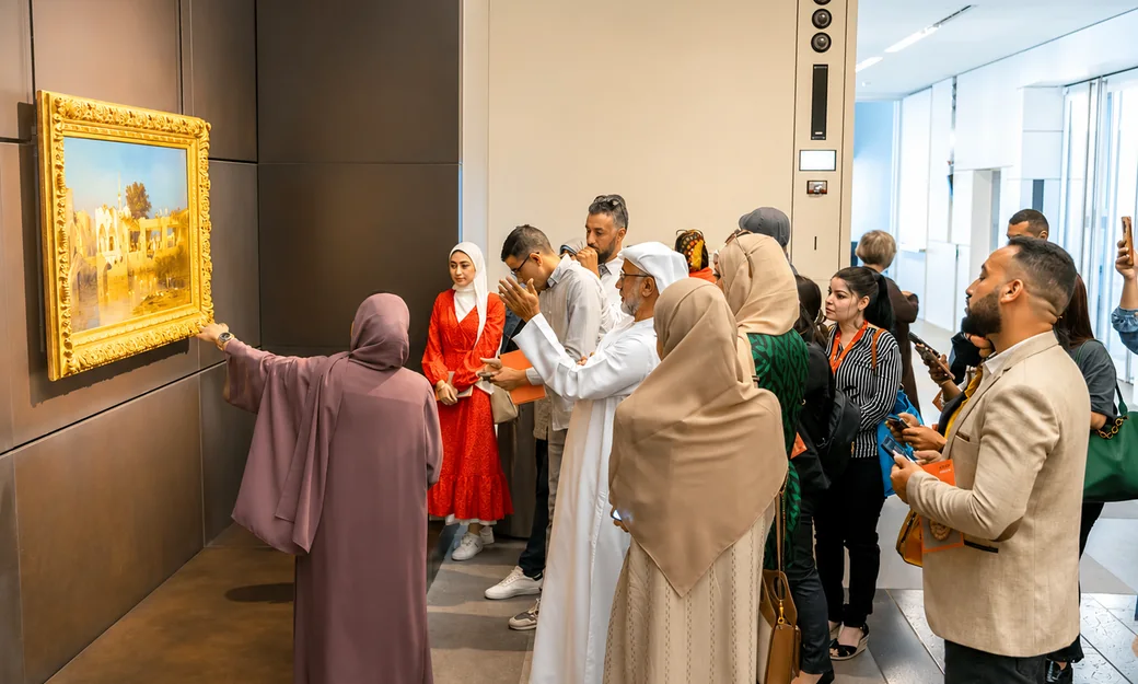 A guided group examining an artwork inside Louvre Abu Dhabi