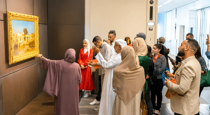 A guided group examining an artwork inside Louvre Abu Dhabi