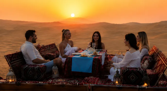 Guests enjoying a private sunset dinner at a dune majlis in Abu Dhabi