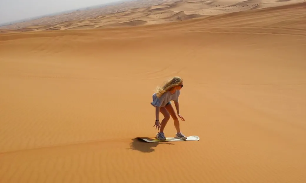 Traveller sandboarding during a private Abu Dhabi desert experience