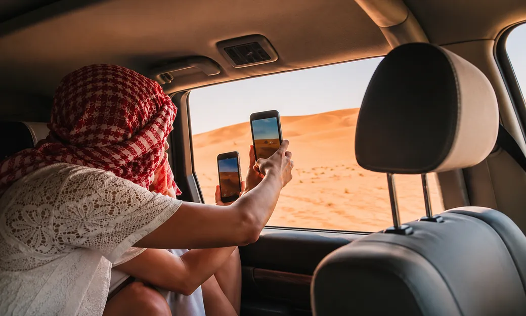 Couple and private 4x4 overlooking an Abu Dhabi desert sunset