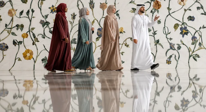 Visitors following a guide past the floral marble wall inside Qasr Al Watan