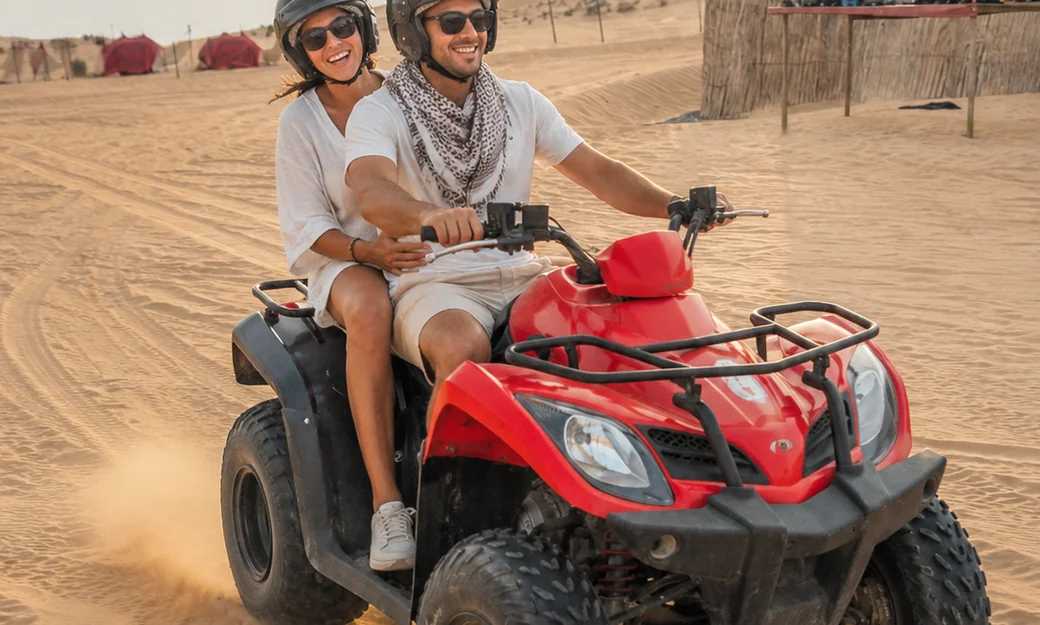 Couple riding a quad bike at a desert camp in Abu Dhabi
