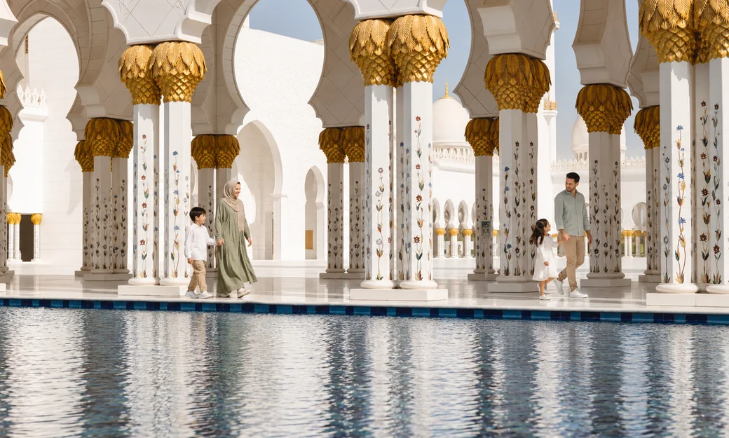 Families walking beside the reflective pools at Sheikh Zayed Grand Mosque
