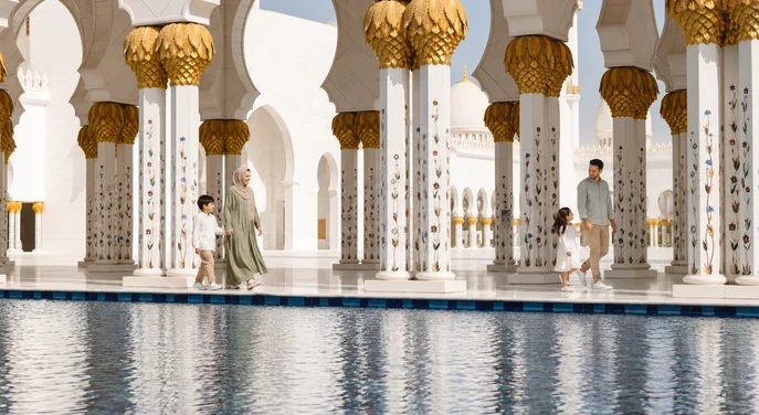 Families walking beside the reflective pools at Sheikh Zayed Grand Mosque