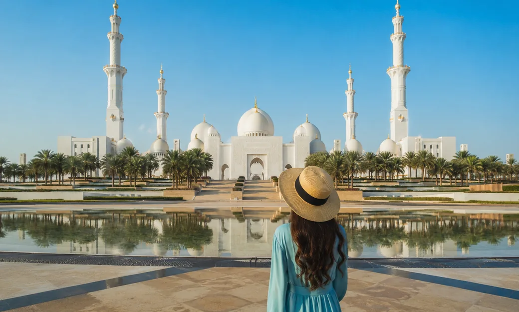 A visitor facing Sheikh Zayed Grand Mosque across the reflecting pool