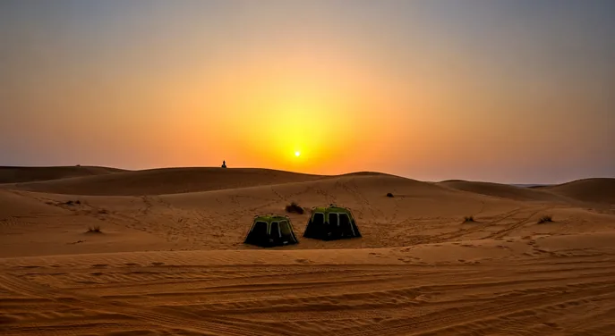 Two private overnight tents beneath an Abu Dhabi desert sunset