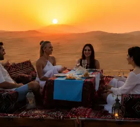 Private group dinner arranged on the Abu Dhabi desert dunes at sunset