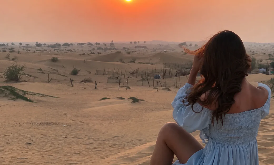 Traveller seated on a dune photographing the Abu Dhabi desert sunset
