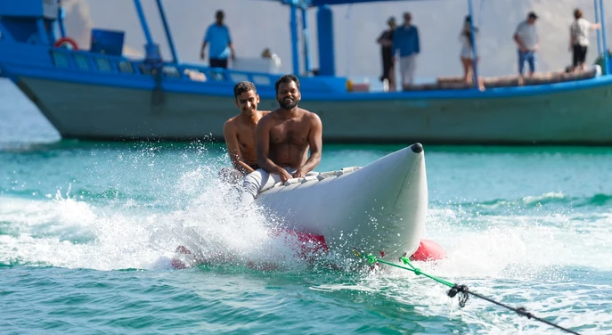 Two guests riding a banana boat during a Khasab dhow cruise
