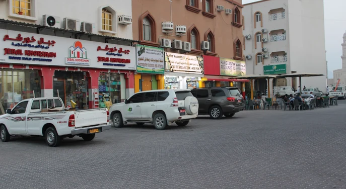 Street scene with shops, restaurants and parked vehicles in Khasab city