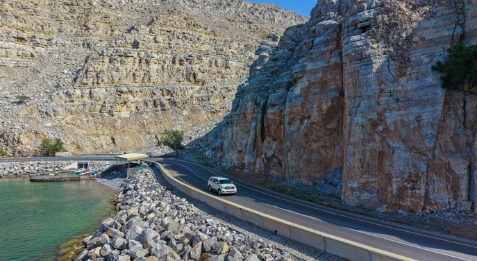 Scenic coastal road winding between the Musandam mountains and turquoise sea