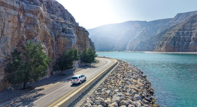 Scenic coastal road winding between the Musandam mountains and turquoise sea