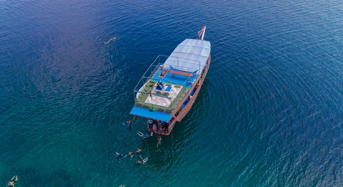 Aerial view of guests snorkelling beside a traditional dhow in Khasab