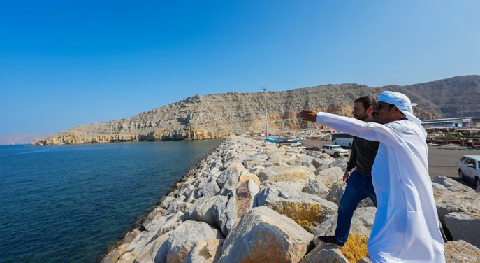 Local guide showing a traveller the Khasab harbour and Musandam coastline