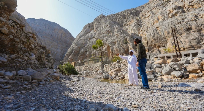 Local guide and traveller exploring a rocky mountain village in Khasab