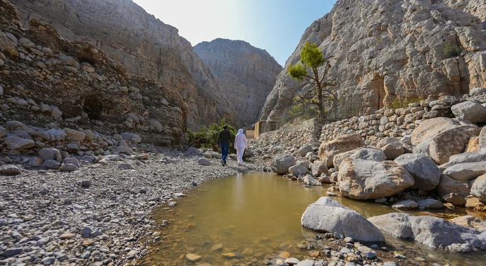 Traveller and local guide walking through a rocky wadi in Khasab