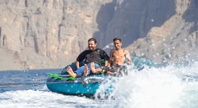 Guests enjoying a fast water activity with Musandam mountains in the background