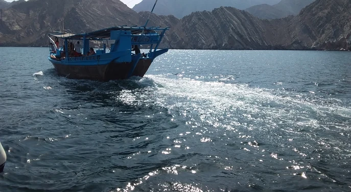 Traditional dhow sailing past the rugged mountains of Musandam