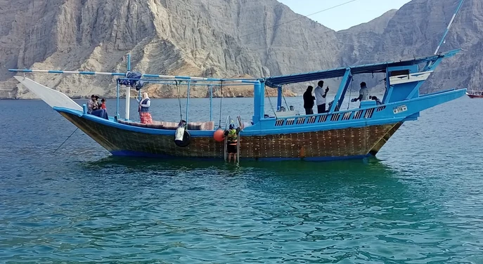 Guests preparing for snorkelling beside a traditional dhow in the Musandam fjords