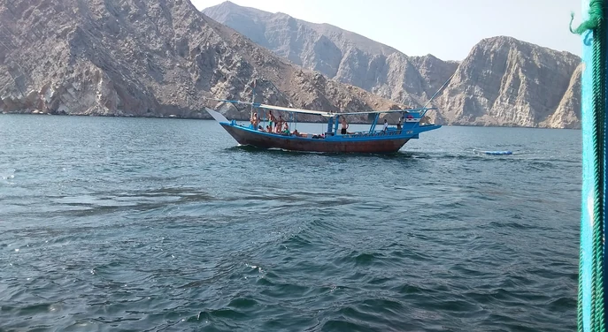 Guests enjoying a dhow cruise among the rocky Musandam fjords
