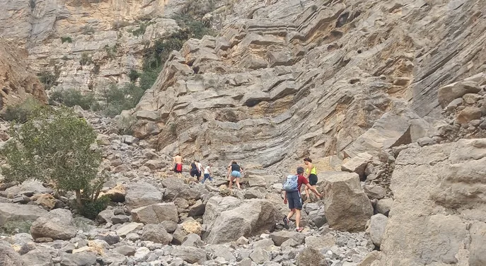 Hikers crossing the rocky Wadi Ain trekking route in Musandam