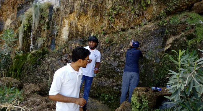 Travellers at the natural mountain waterfall in Wadi Ain, Musandam