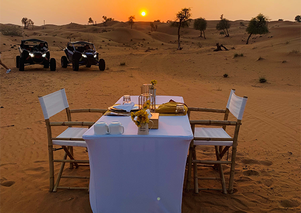 Arabic BBQ dinner table set in the desert at dusk beside dune buggies